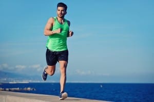 Attractive strong athlete running along the sea at evening