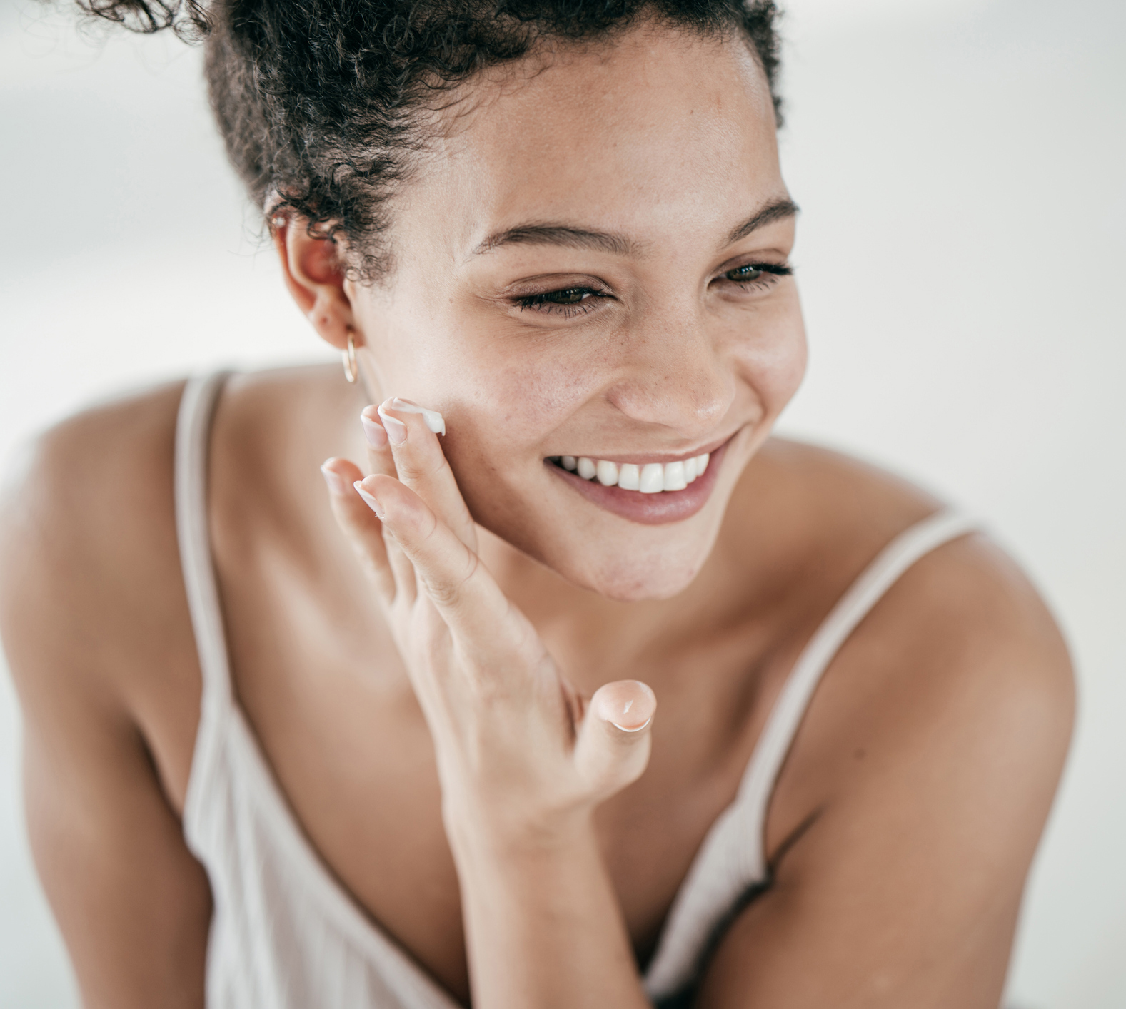 Smiling young women applying moisturiser to her face Yearly Skin Check