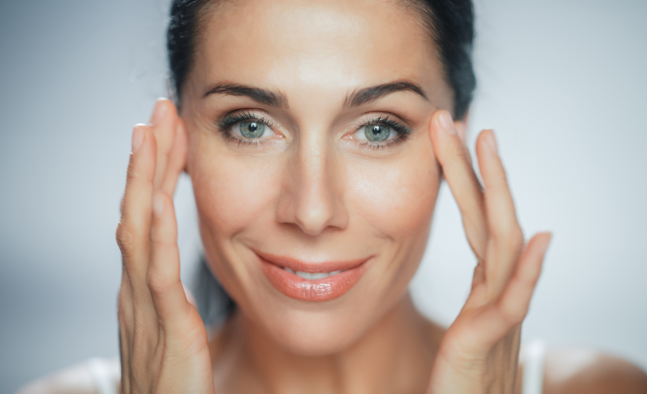 Beautiful Caucasian Woman Touches Her Perfect Face with Soft Skin, Smiling. Female Enjoying Her Beauty, High Self Esteem, Wellness. Natural Cosmetic Skincare Products. Portrait on Isolated Background Dysport® in Pflugerville, TX